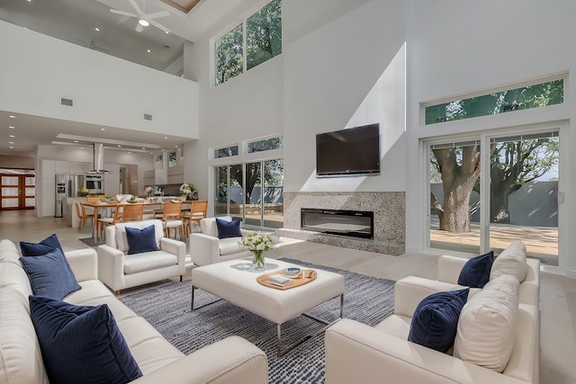 living area with a high ceiling, a premium fireplace, wood finished floors, and recessed lighting