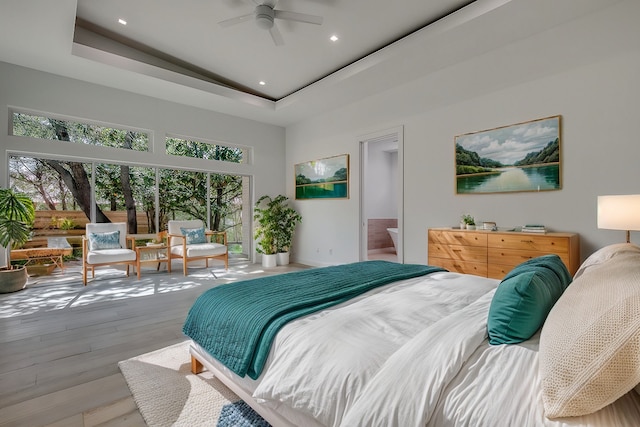 bedroom featuring wood-type flooring, baseboards, a raised ceiling, and recessed lighting