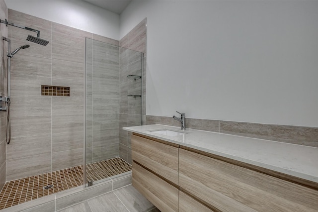 bathroom with a tile shower and vanity