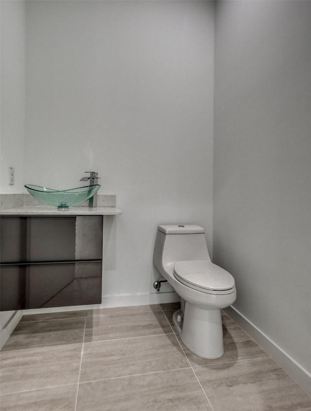 bathroom with baseboards, vanity, and toilet