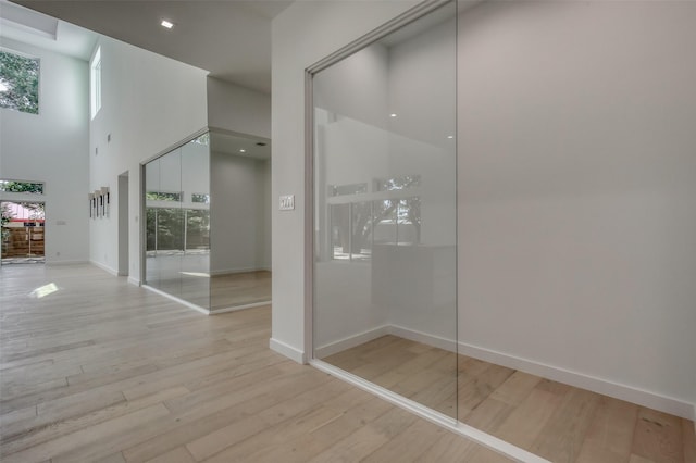 interior space featuring a high ceiling, baseboards, and wood finished floors