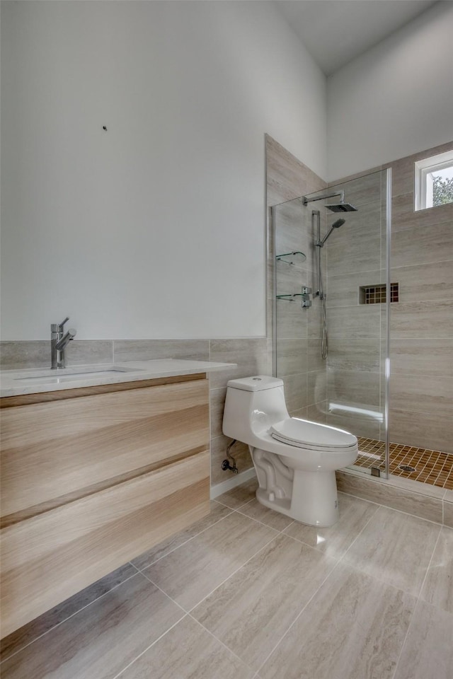bathroom featuring toilet, tile walls, a stall shower, and vanity