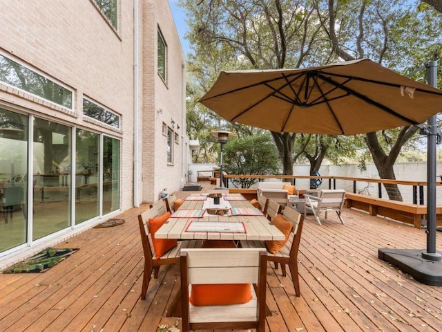 wooden terrace with outdoor dining area and fence