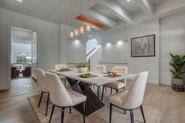 dining space featuring light wood-type flooring, beam ceiling, and baseboards