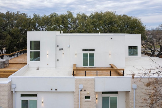 back of house featuring stucco siding, a balcony, and central AC unit