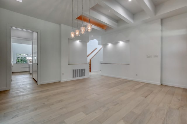 spare room featuring visible vents, baseboards, stairs, light wood-type flooring, and beam ceiling