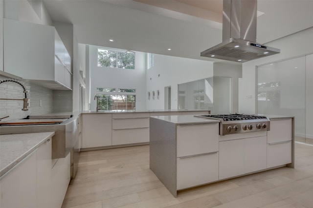 kitchen featuring stainless steel gas cooktop, decorative backsplash, white cabinets, island range hood, and modern cabinets