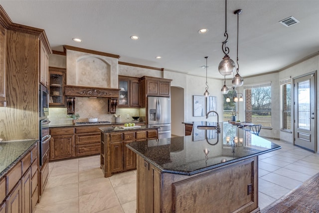 kitchen featuring arched walkways, stainless steel appliances, a spacious island, visible vents, and a sink