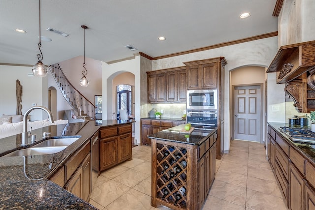 kitchen with visible vents, arched walkways, appliances with stainless steel finishes, dark stone countertops, and a sink