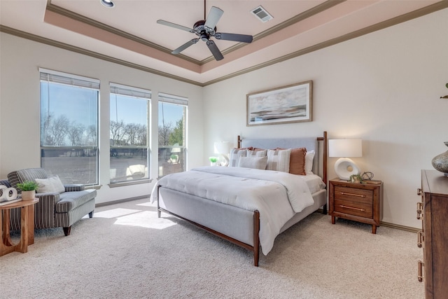 bedroom with light colored carpet, visible vents, baseboards, ornamental molding, and a tray ceiling