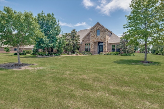 view of front of home with stone siding, a front lawn, and brick siding