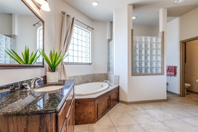 bathroom featuring baseboards, vanity, toilet, and a bath