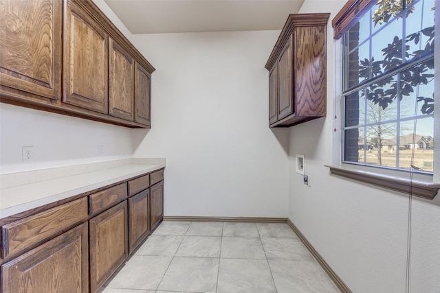 washroom with cabinet space, baseboards, hookup for a washing machine, electric dryer hookup, and light tile patterned flooring