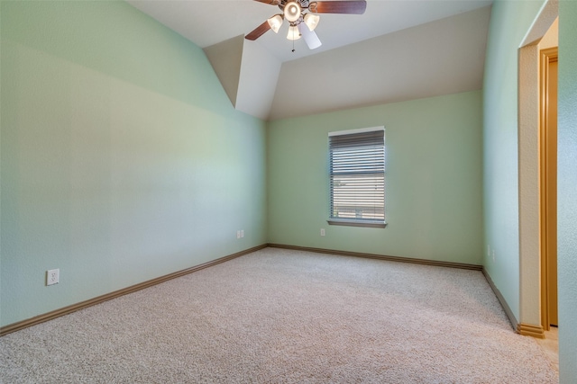 spare room with light carpet, vaulted ceiling, baseboards, and ceiling fan