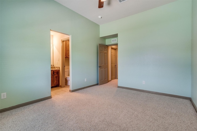 unfurnished bedroom featuring lofted ceiling, connected bathroom, light colored carpet, visible vents, and baseboards