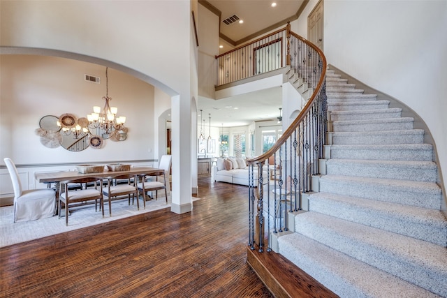 interior space featuring a towering ceiling, wood finished floors, visible vents, and a chandelier