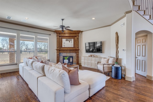 living area featuring ornamental molding, a tiled fireplace, wood finished floors, and visible vents