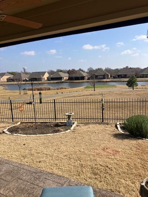 view of yard featuring a residential view, a water view, and fence