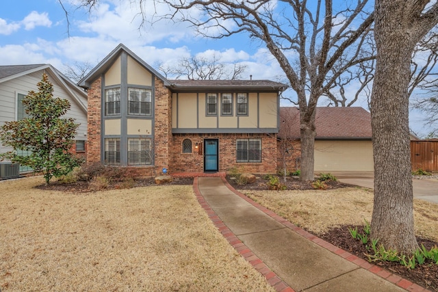 tudor house with an attached garage, central AC, brick siding, driveway, and stucco siding