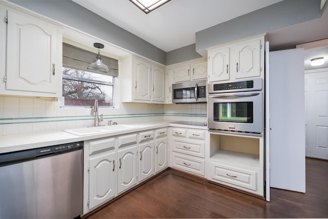 kitchen featuring appliances with stainless steel finishes, white cabinets, a sink, and tasteful backsplash