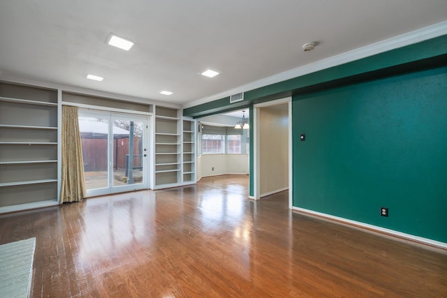 spare room with built in features, baseboards, visible vents, and wood finished floors