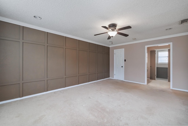 interior space featuring visible vents, ornamental molding, a decorative wall, and a textured ceiling