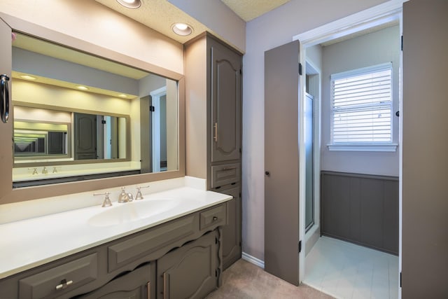 full bath featuring a wainscoted wall, walk in shower, and vanity