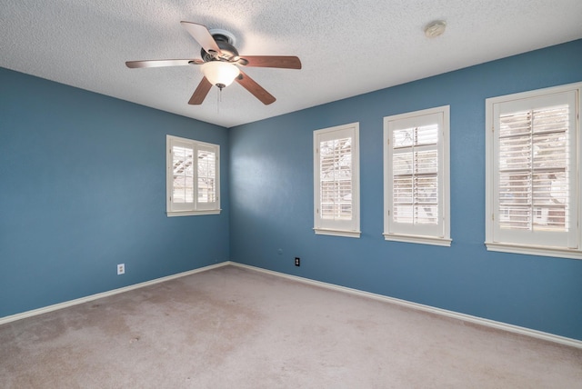 spare room with a textured ceiling, carpet, a ceiling fan, and baseboards