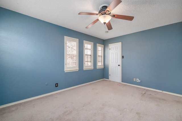 empty room featuring a textured ceiling, carpet floors, a ceiling fan, and baseboards