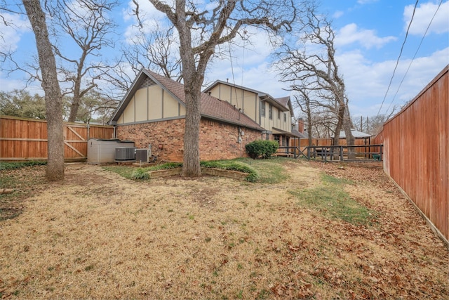 view of side of home with a fenced backyard, central AC, and brick siding