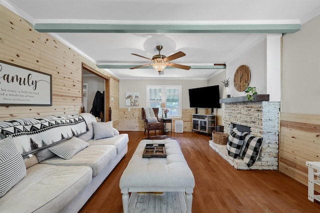 living area featuring wood walls, a fireplace, crown molding, and wood finished floors