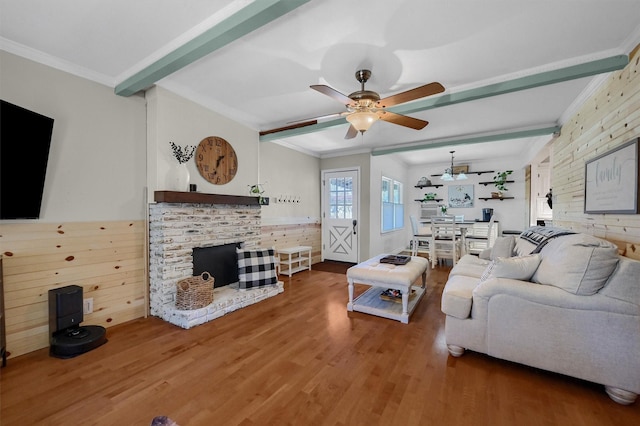 living area featuring ornamental molding, a fireplace, wood finished floors, and beam ceiling