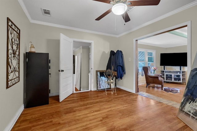 interior space with baseboards, visible vents, wood finished floors, freestanding refrigerator, and crown molding