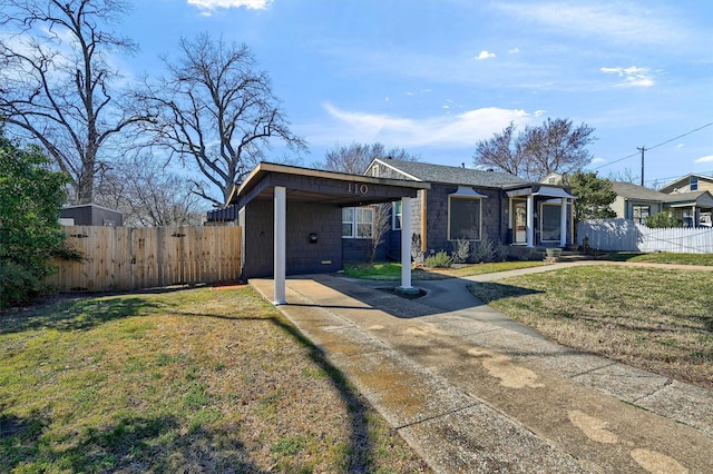 view of front of house featuring a front yard, concrete driveway, and fence