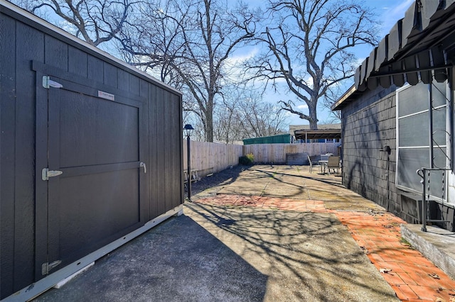 view of yard featuring a patio area, a fenced backyard, an outdoor structure, and a storage shed