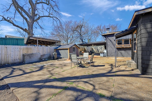 exterior space featuring outdoor dining space, a fenced backyard, a storage unit, and an outbuilding