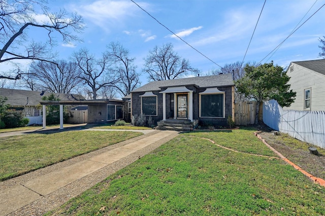 view of front of home featuring a front yard, roof with shingles, fence, and an attached carport