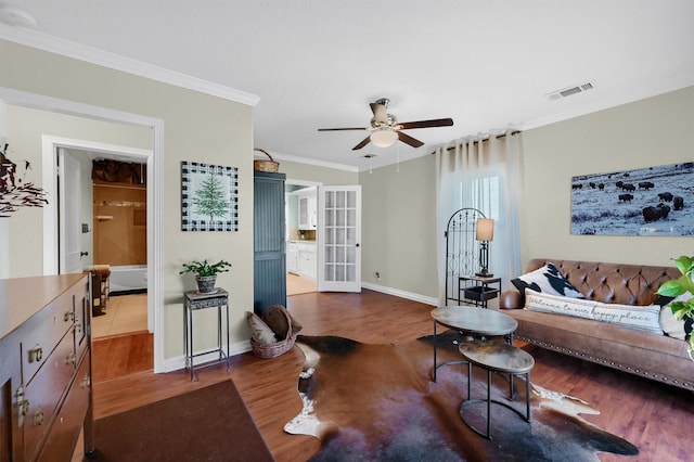 living room with visible vents, ornamental molding, a ceiling fan, wood finished floors, and baseboards