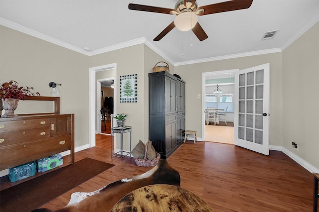 interior space with visible vents, ornamental molding, a ceiling fan, wood finished floors, and baseboards