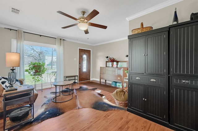 entrance foyer featuring a ceiling fan, visible vents, ornamental molding, and wood finished floors