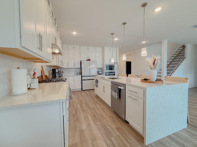 kitchen featuring stainless steel appliances, light wood-style flooring, and white cabinets