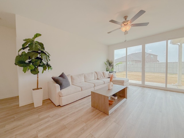 living room featuring light wood-style floors, baseboards, and a ceiling fan