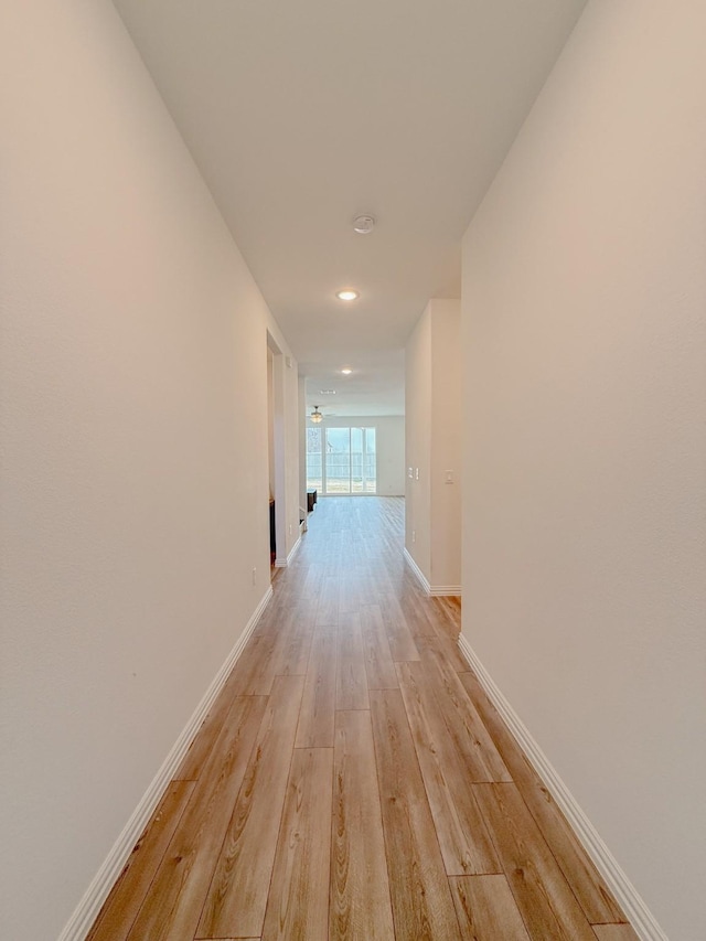 hall featuring light wood-style flooring and baseboards