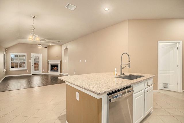 kitchen featuring light tile patterned floors, visible vents, a lit fireplace, a sink, and dishwasher