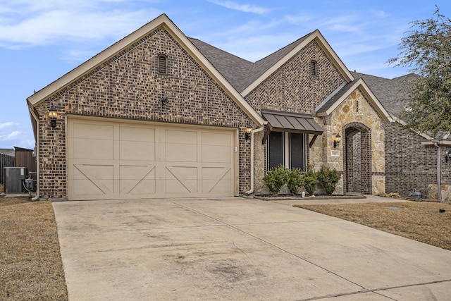 french country home featuring an attached garage, brick siding, central AC, and driveway