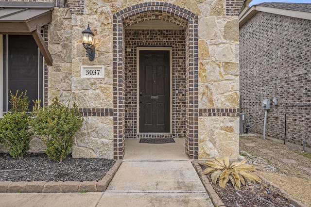 view of exterior entry with stone siding and brick siding