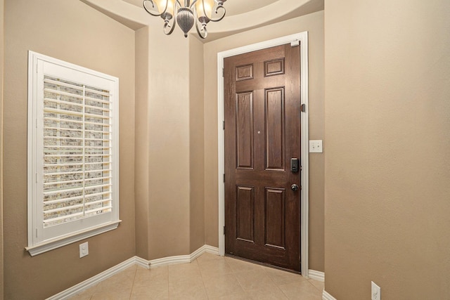 foyer entrance featuring light tile patterned floors, baseboards, and a chandelier