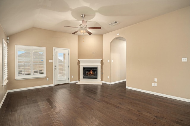 unfurnished living room featuring visible vents, a fireplace with raised hearth, dark wood-type flooring, baseboards, and a ceiling fan