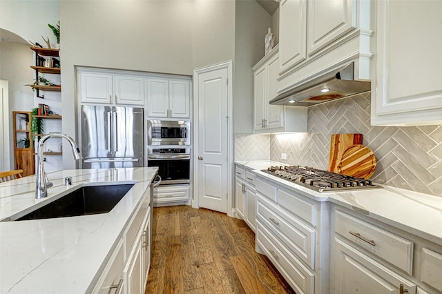 kitchen featuring decorative backsplash, dark wood-style floors, appliances with stainless steel finishes, white cabinetry, and a sink