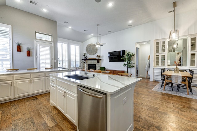 kitchen with a fireplace, vaulted ceiling, a sink, wood finished floors, and dishwasher